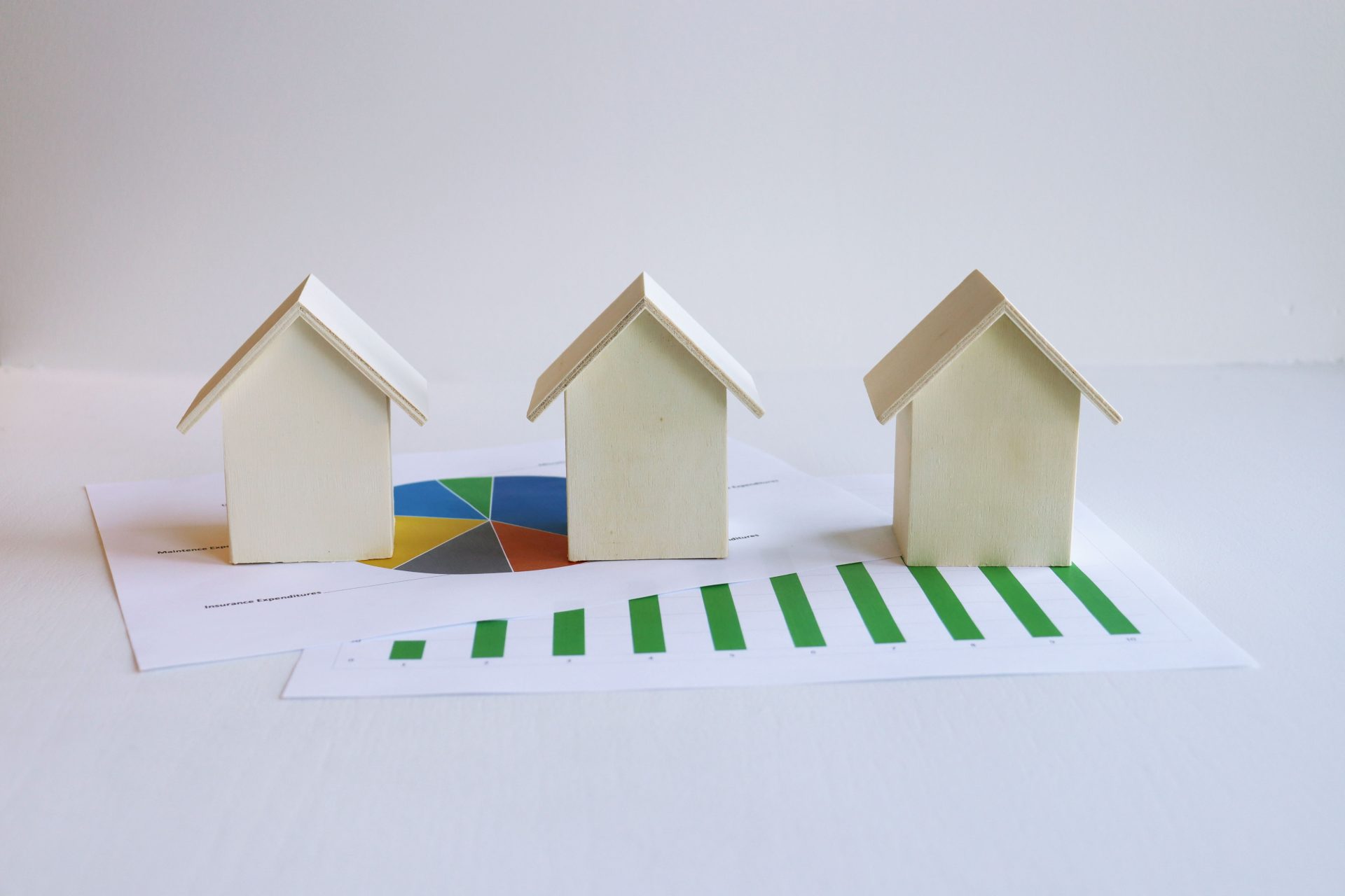 Wooden model houses on graphs depict real estate market analysis and trends.